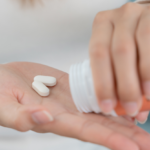 A woman’s hand reaching for an antibiotic pill from a blister pack, illustrating missed antibiotic doses and what to do next.